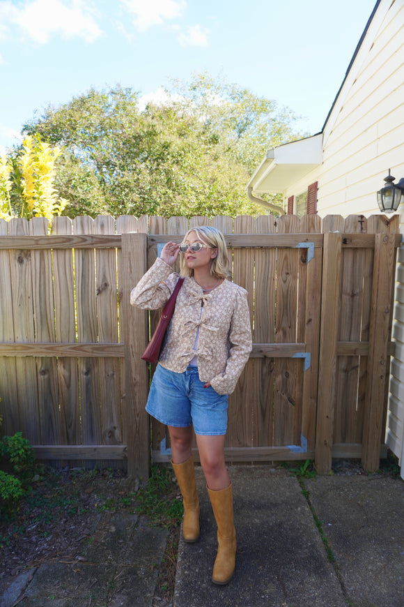 Woman standing in a backyard with a wooden fence and trees in the background