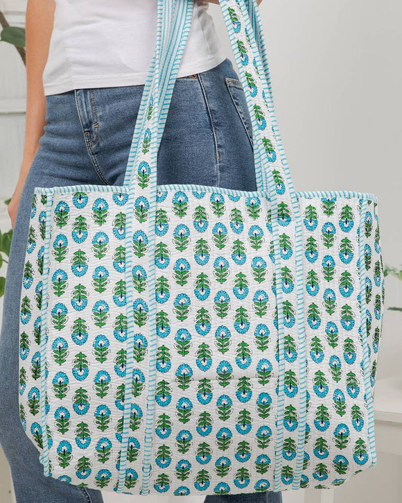 Person holding a patterned tote bag with blue and green design