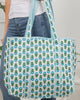Person holding a patterned tote bag with blue and green design
