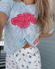 Person wearing a light blue tie-dye shirt with a pink flower design and white shorts with blue floral pattern.