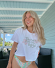Woman wearing a white t-shirt with text and colorful bikini bottoms on a patio.