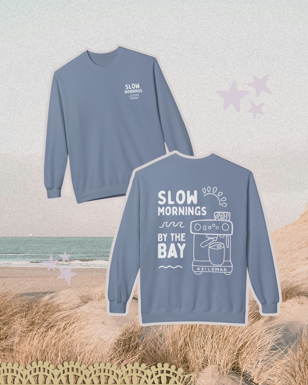 Blue sweatshirt with 'Slow Mornings by the Bay' text and graphics on a beach background