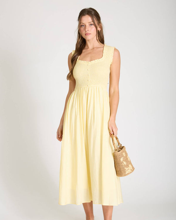 Woman wearing a yellow dress holding a gold handbag on a white background
