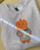Gray sweatshirt with a cartoon character on a yellow textured surface
