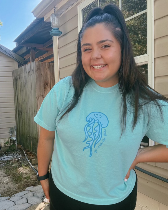 Woman wearing a light blue t-shirt with a jellyfish design outdoors.