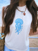 Person wearing a white t-shirt with a blue jellyfish design on a beach.