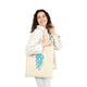 A person holding a beige cotton tote bag with a hand-drawn blue jellyfish design.