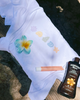 Hawaiian Tropic dark tanning lotion bottle on a white garment with shell designs.