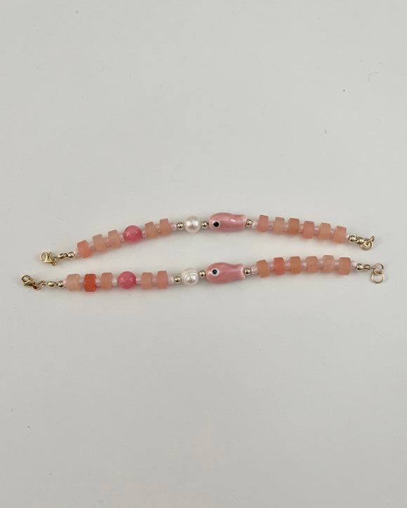 Beaded bracelet with pink and gold accents on a white background