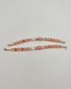Beaded bracelet with pink and gold accents on a white background