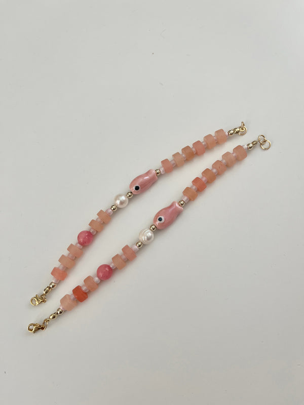 Beaded bracelets with pink, white, and gold beads on a white background
