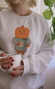 Person wearing a sweater with a cartoon character holding a mug indoors.