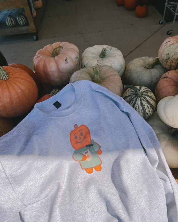 Gray sweatshirt with a pumpkin design in front of pumpkins