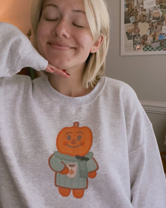 Person wearing a gray sweatshirt with a pumpkin graphic design.