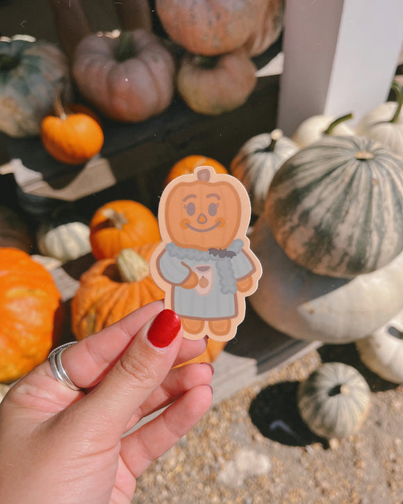hand holding a pumpkin girl character sticker in front of pumpkins