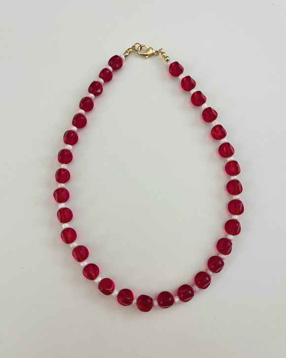 Beaded necklace with red beads on a light gray background