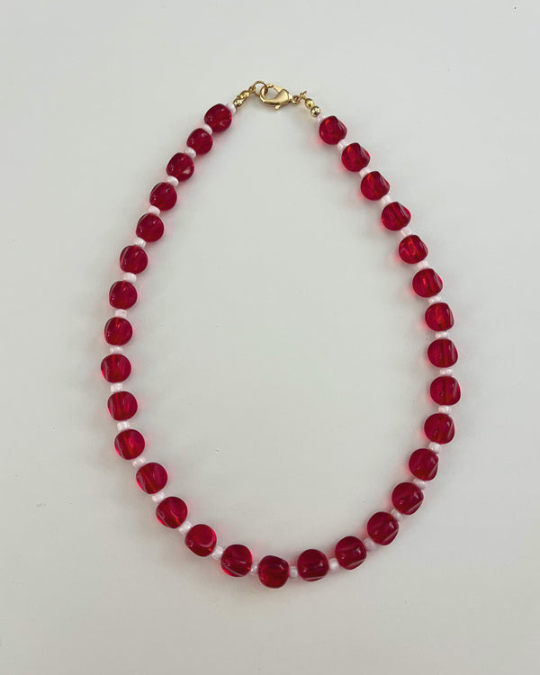 Beaded necklace with red beads on a light gray background