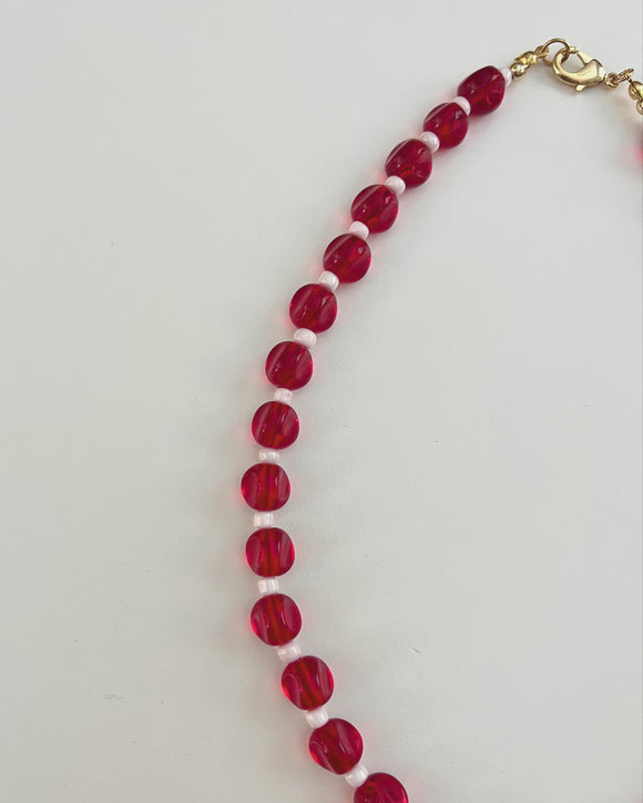Necklace with red beads and a gold clasp on a white background