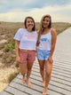 Two women standing on a wooden boardwalk at the beach, wearing matching t-shirts with 'Virginia Beach' text.