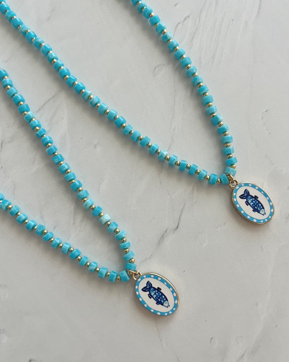 Necklace with blue beaded chain and decorative clasp on a light gray background