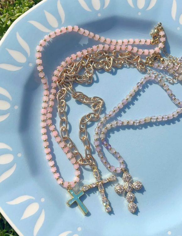 Necklace with pink beads and gold chain on a light blue plate